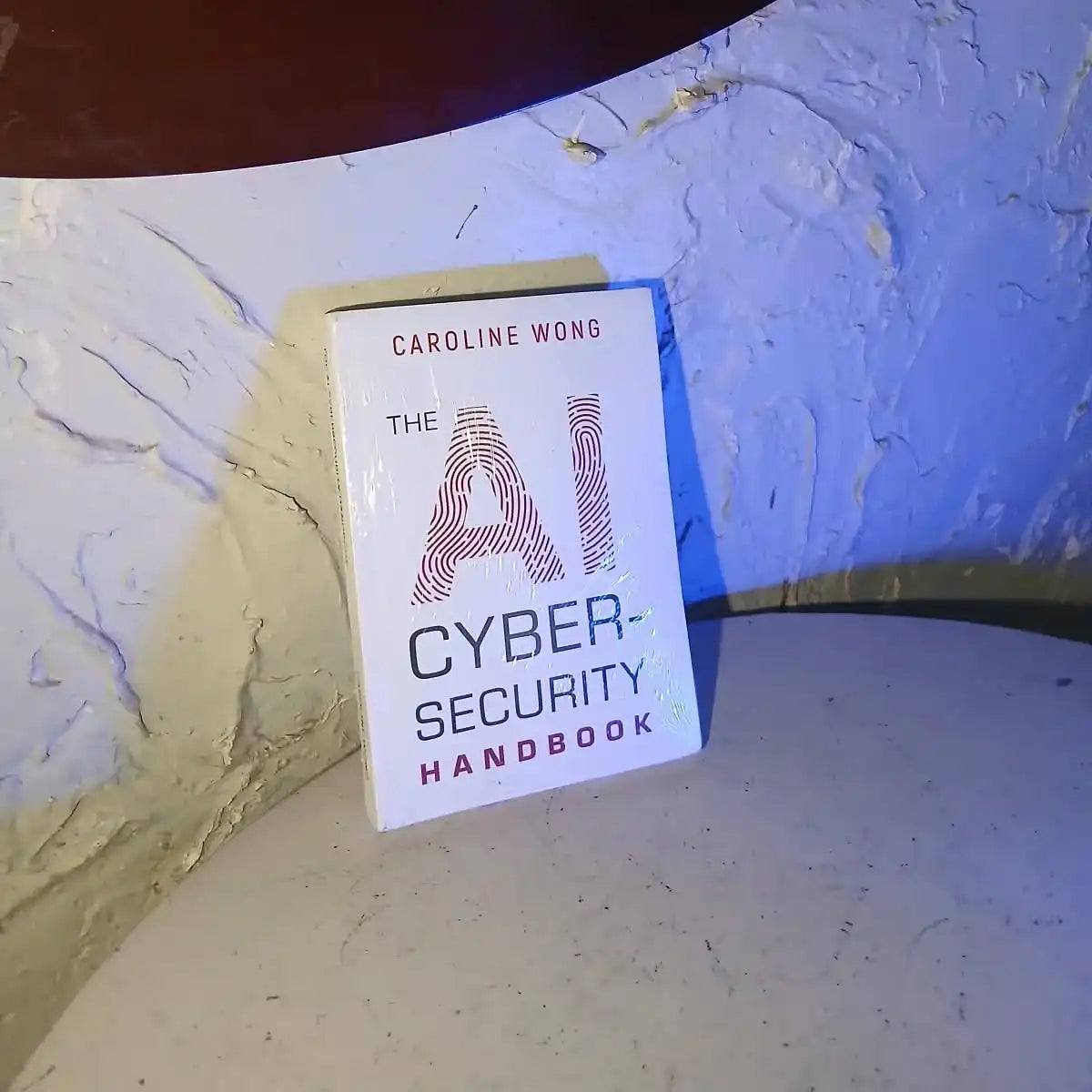 The AI Cyber-Security Handbook book by Caroline Wong on a textured surface.