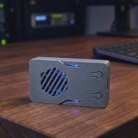 Compact grey pentesting hardware device with blue LED lights on a wooden desk.